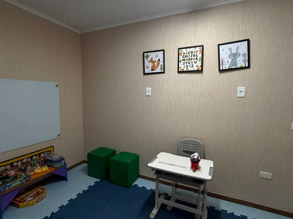 Sala de atendimento com mesa infantil, lousa e pufes